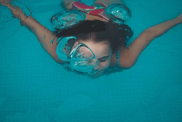 bambina nuota e fa le bolle sott'acqua