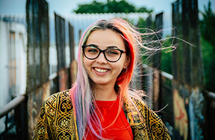 Ragazza sorridente con gli occhiali e i capelli colorati